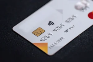 Carte avantage CSE | La journée du CSE | La journée du CSE Close-up of a white credit card with a gold chip and contactless symbol on dark fabric surface.